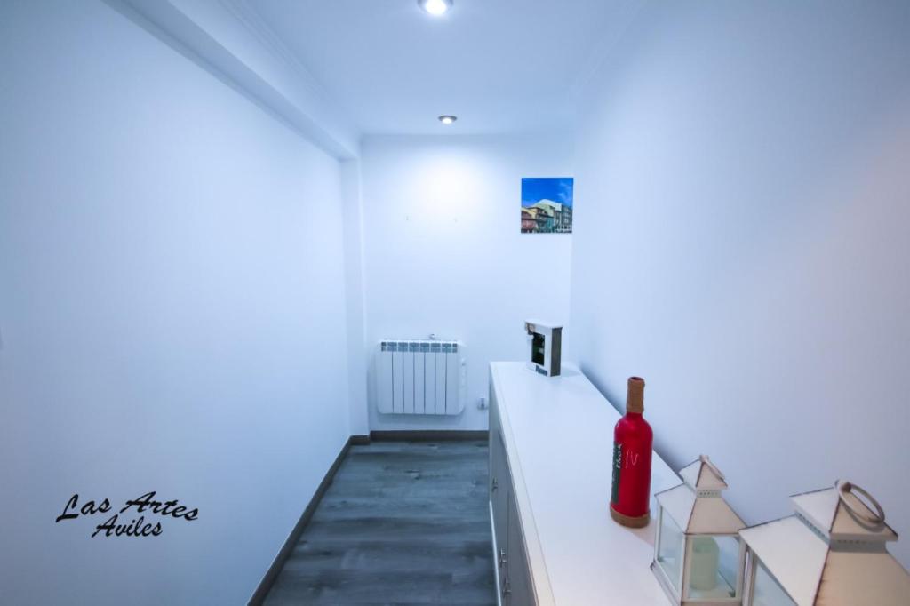 阿维莱斯Piso las Artes的白色客房,在柜台上提供一瓶葡萄酒
