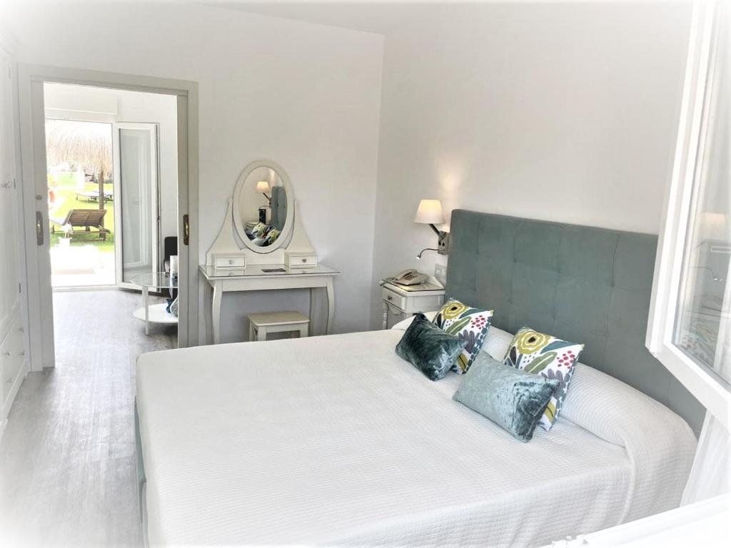 马拉加马拉加毕加索酒店的卧室配有带枕头和镜子的白色床