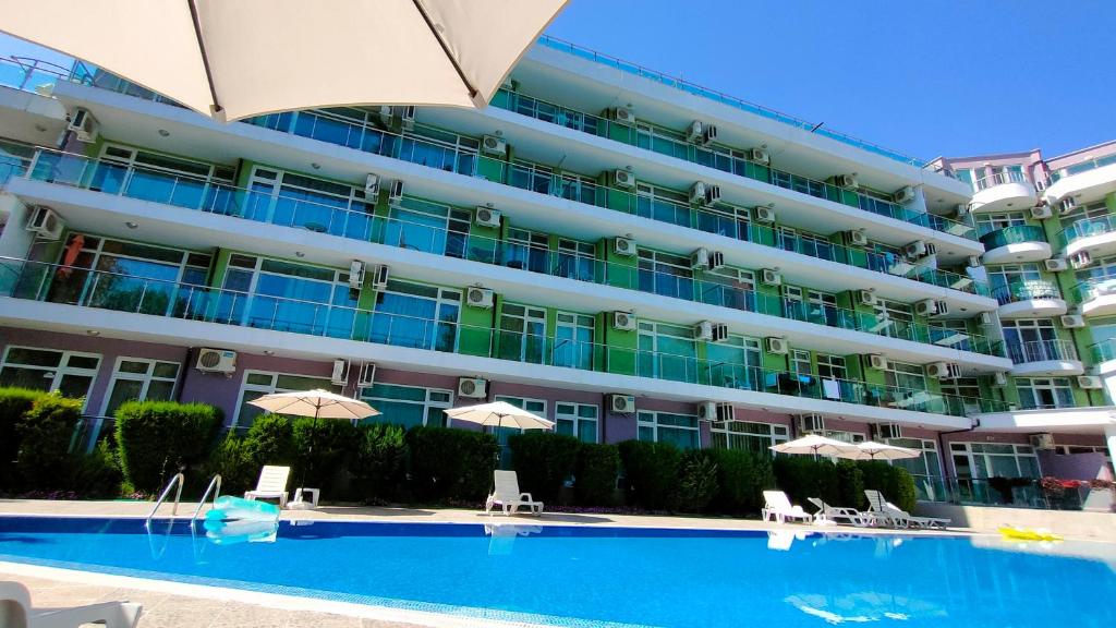 阳光海滩Sunny Beach Studio in Apartcomplex Solmarine的一座带游泳池和遮阳伞的大型公寓大楼