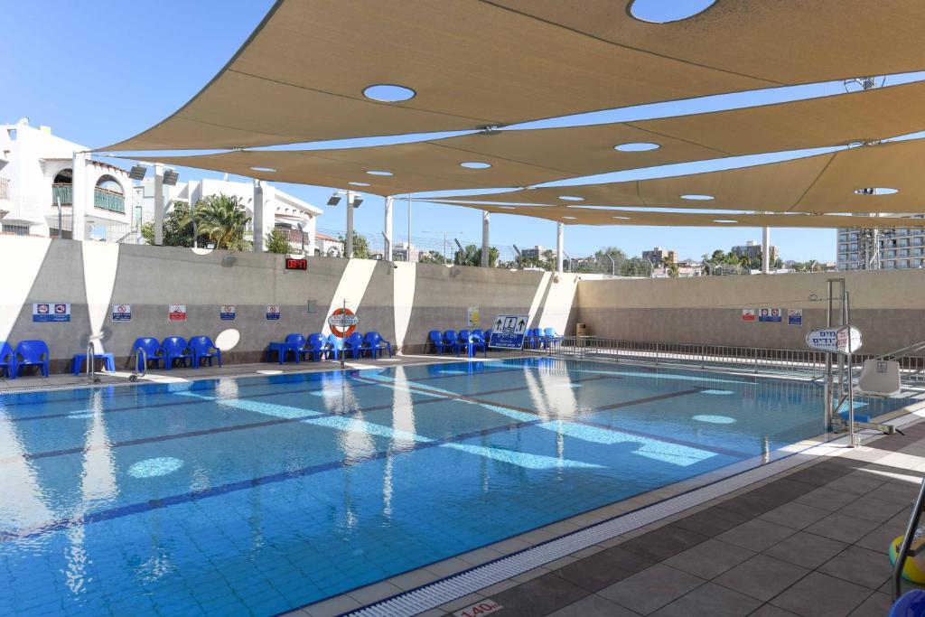 埃拉特嗨 - 埃拉特旅舍的一个带蓝色椅子和遮阳伞的大型游泳池