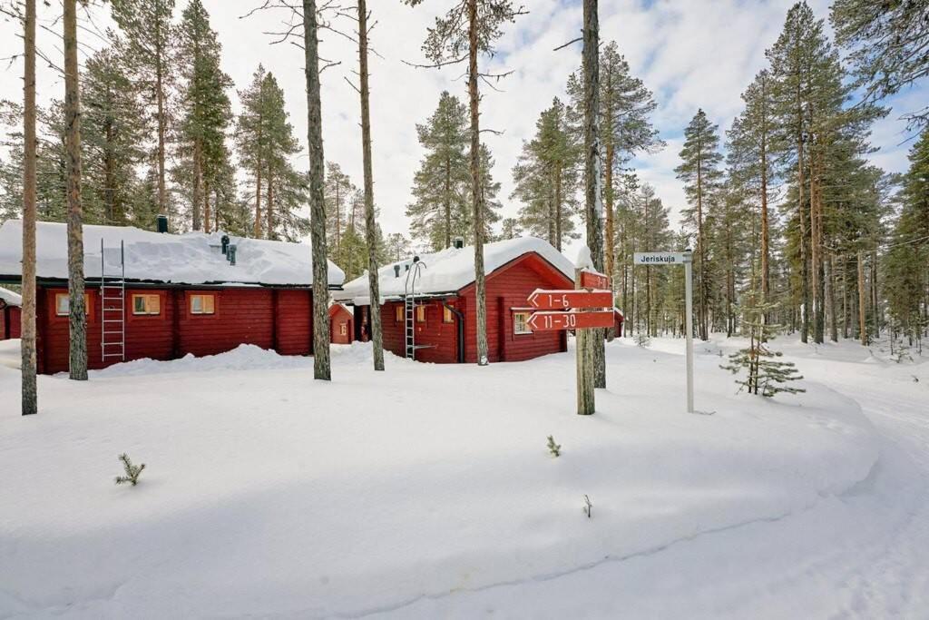 穆奥尼奥Mökki Jerisjärven rannalla的雪中的一个红色小屋,有树