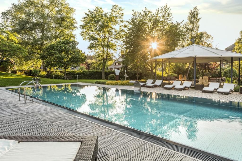 欣特察尔滕阿德勒公园酒店的一个带椅子的游泳池和一个凉亭