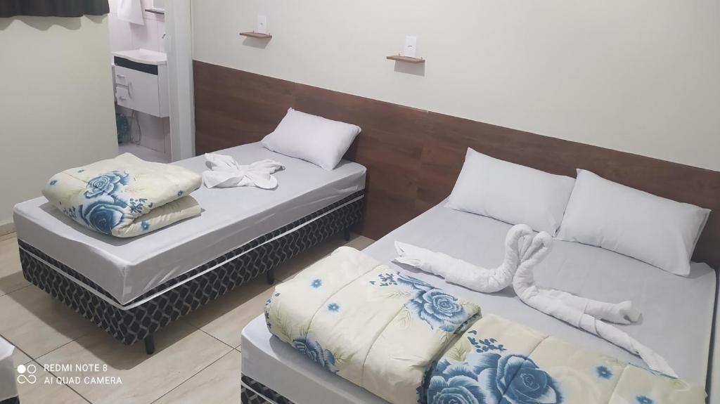 阿帕雷西达Pousada Quarto completo ar,wi fi e garagem gratuita的白色和蓝色的客房内的两张床