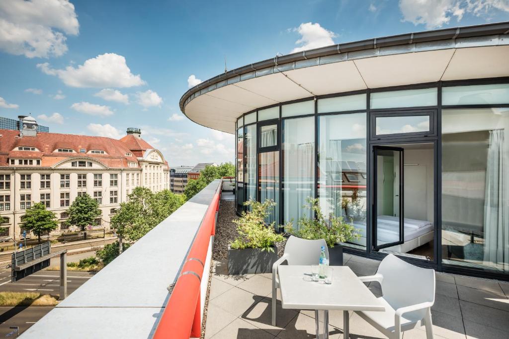 莱比锡Art Hotel City Leipzig的大楼内的阳台配有桌椅