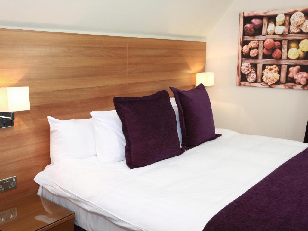 伯恩茅斯巧克力盒旅馆的卧室配有一张带紫色枕头的大型白色床。