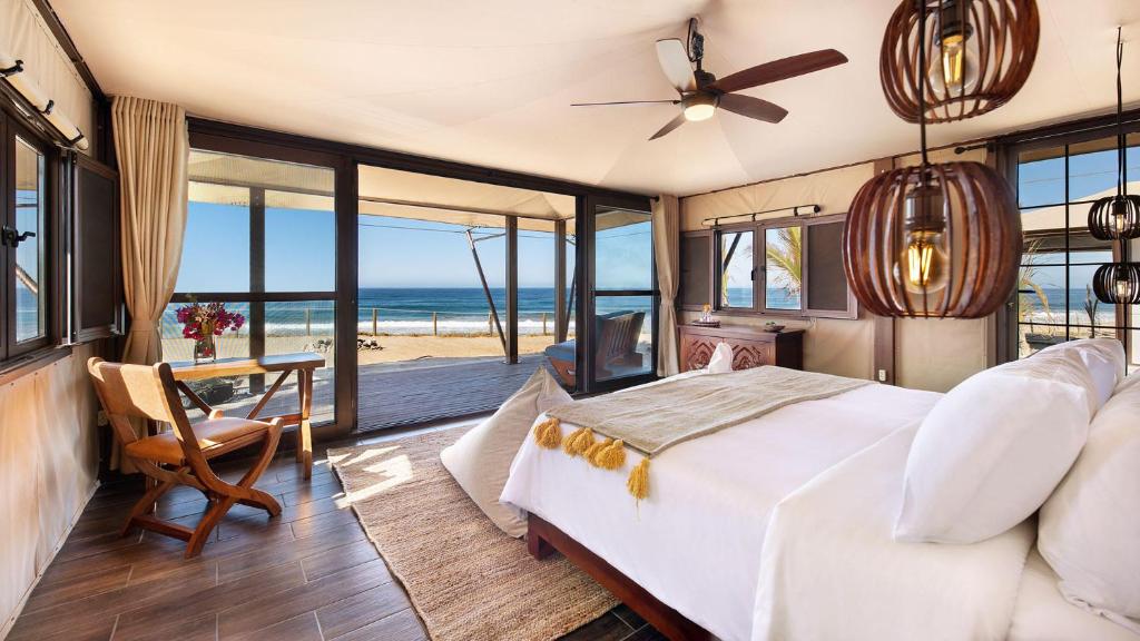 托多斯桑托斯Villa Santa Cruz的一间卧室配有一张床,享有海滩美景