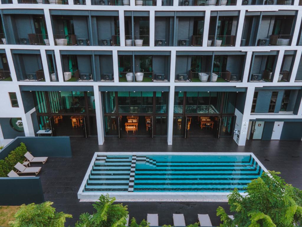 尖竹汶Blu Monkey Hub and Hotel Chanthaburi的一座大型建筑,前面设有一个游泳池