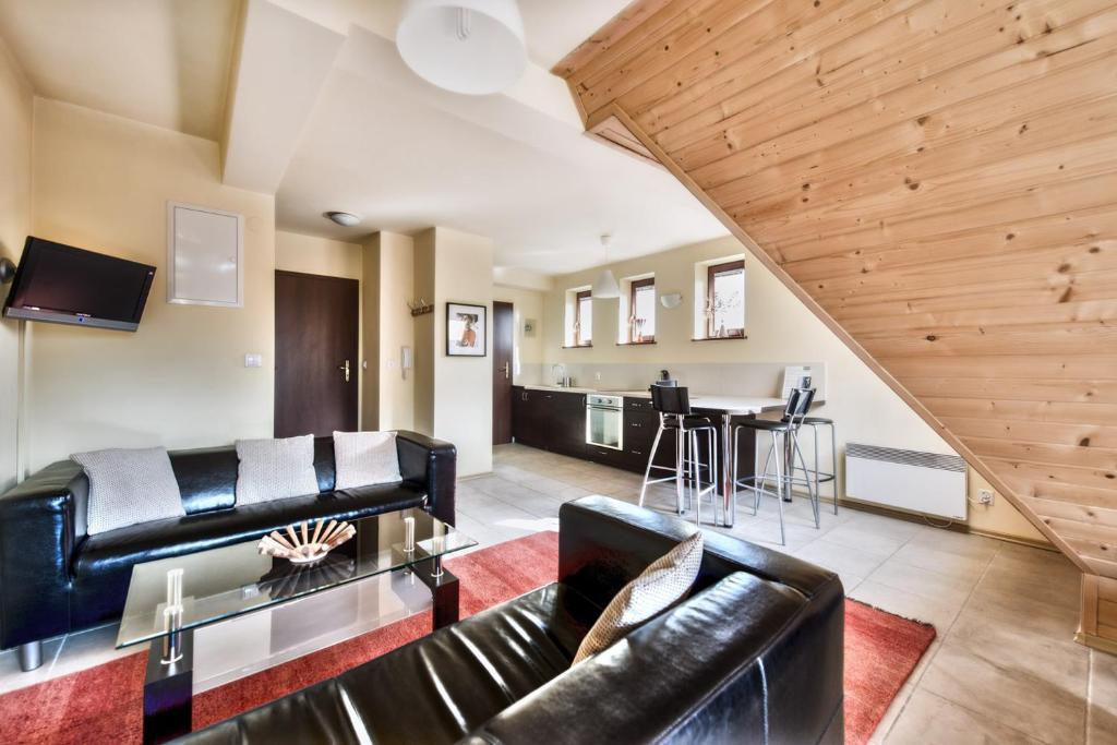 考斯赛力克Apartamenty Sun & Snow Kościelisko Chotarz z basenem的客厅配有皮革家具和木制天花板