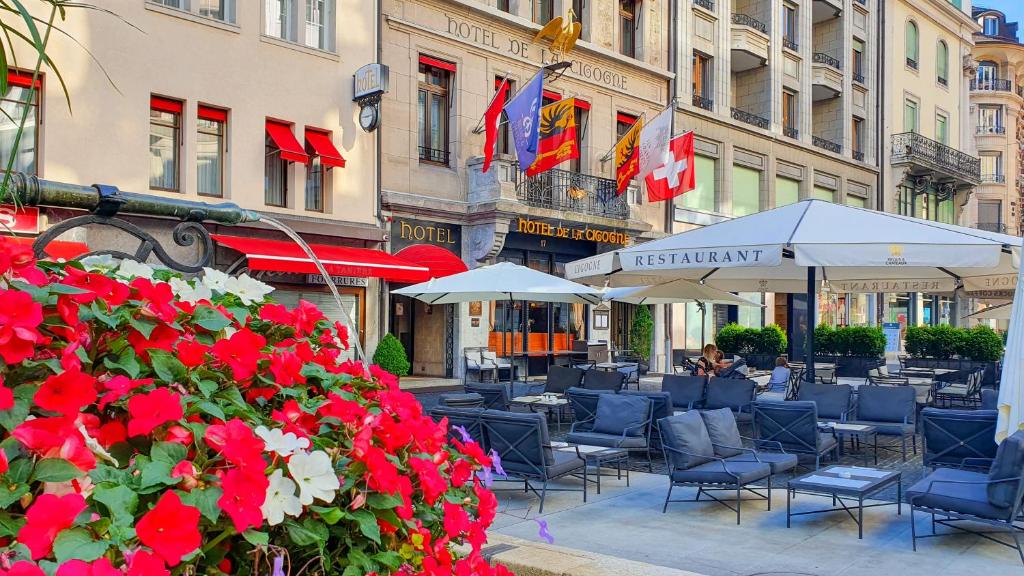 日内瓦白鹤酒店的庭院配有桌椅和红色鲜花