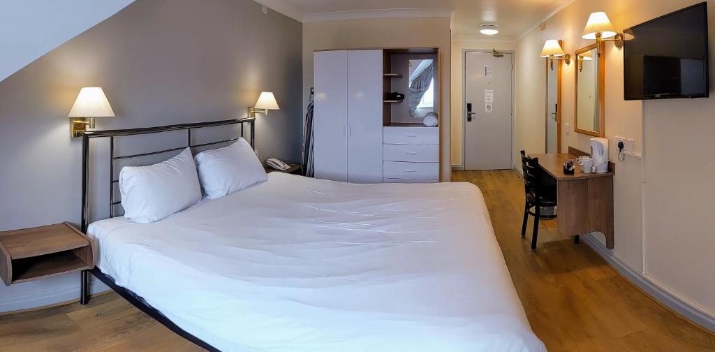 奥尔德姆247酒店.com的卧室配有一张白色大床和一张书桌