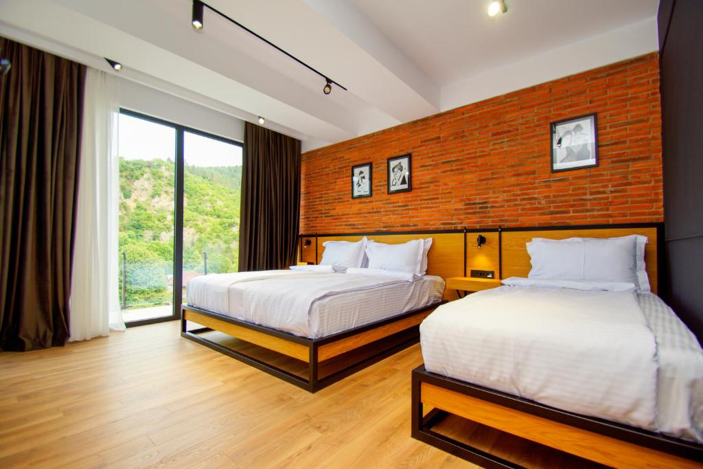 博尔若米Borjomi Bridge Hotel的一间卧室设有两张床和砖墙