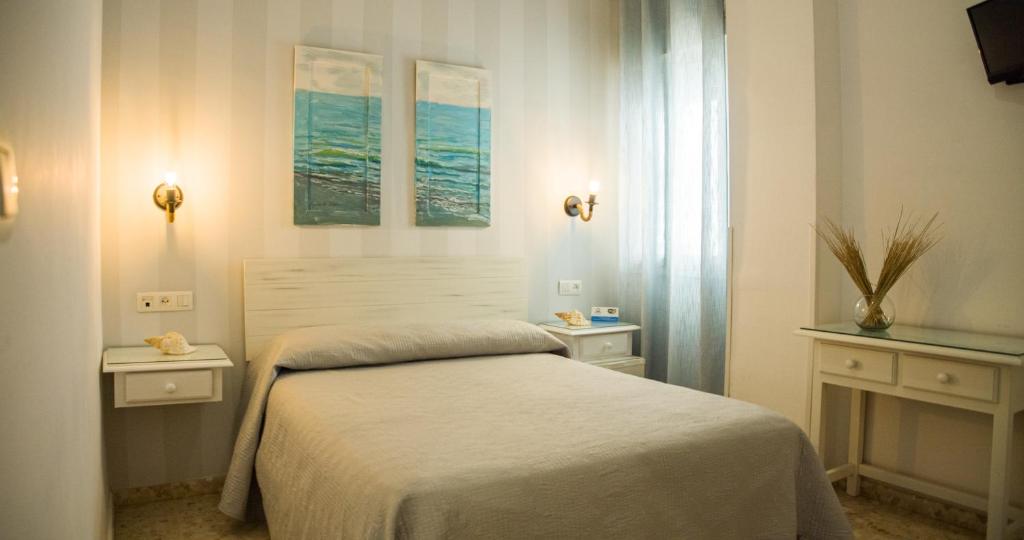 蓬塔翁布里亚Hostal Patio Andaluz的一间卧室设有床、两张桌子和一扇窗户