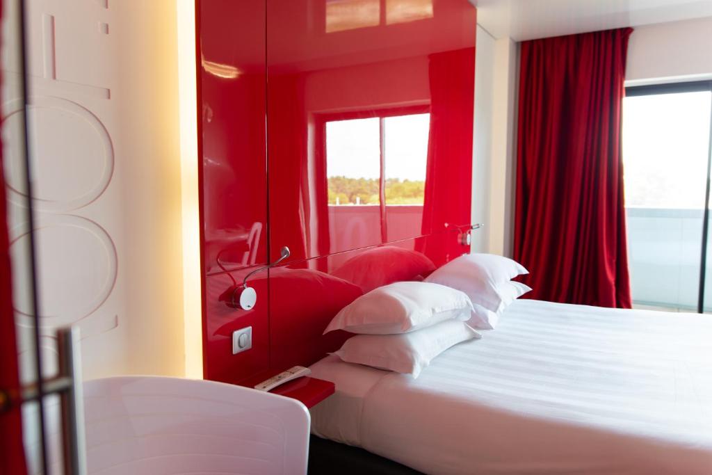 拉特斯特德布赫Zenitude Hôtel Résidences Bassin d'Arcachon的卧室设有红色的墙壁和一张带白色枕头的床