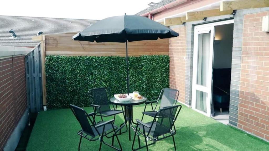 彼得伯勒Blue Apartment in Peterborough的庭院配有桌椅和遮阳伞。