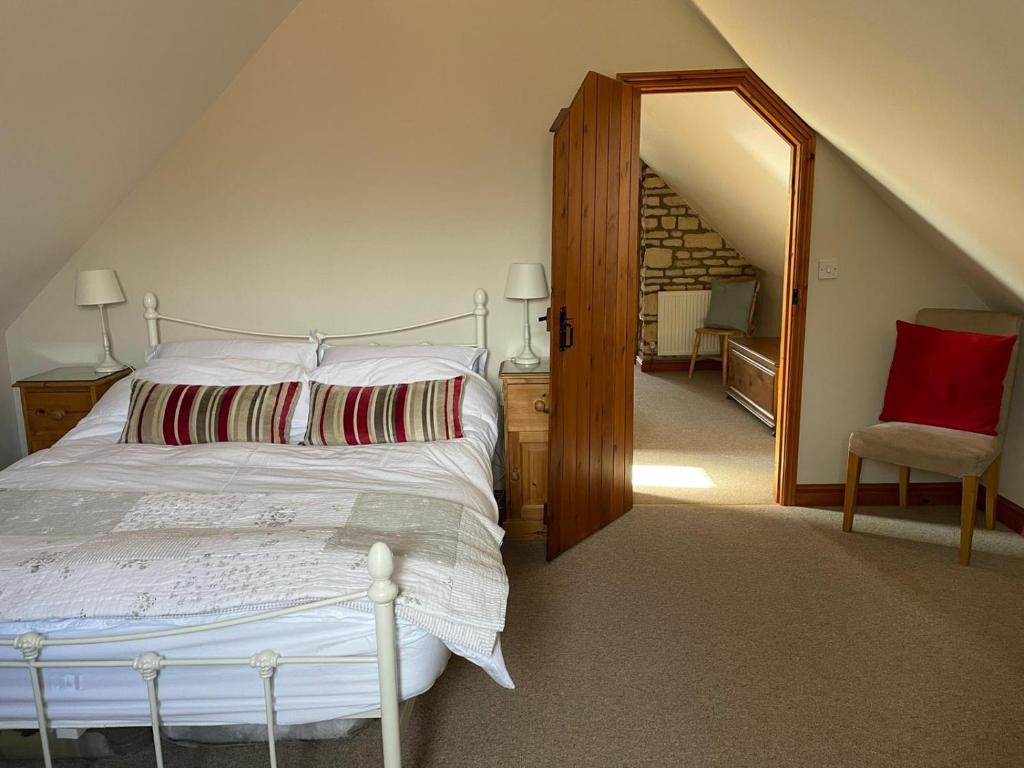 格兰瑟姆Farriers Cottage的卧室配有白色的床和红色椅子