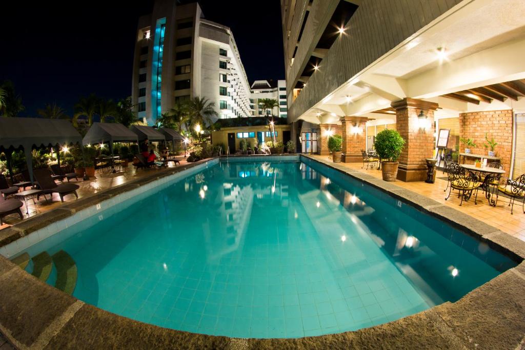 马尼拉Copacabana Apartment Hotel的夜间酒店的大型游泳池