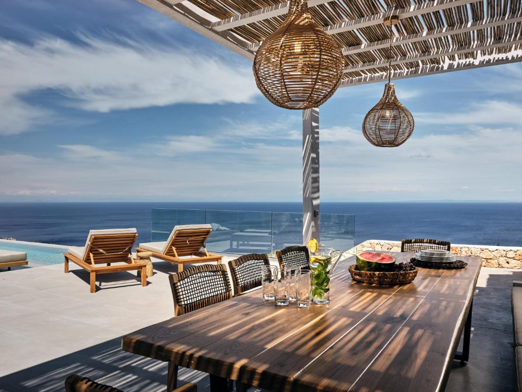 圣尼古拉奥斯Etheria Luxury Villas & Suites的一张带椅子的木桌,享有海景