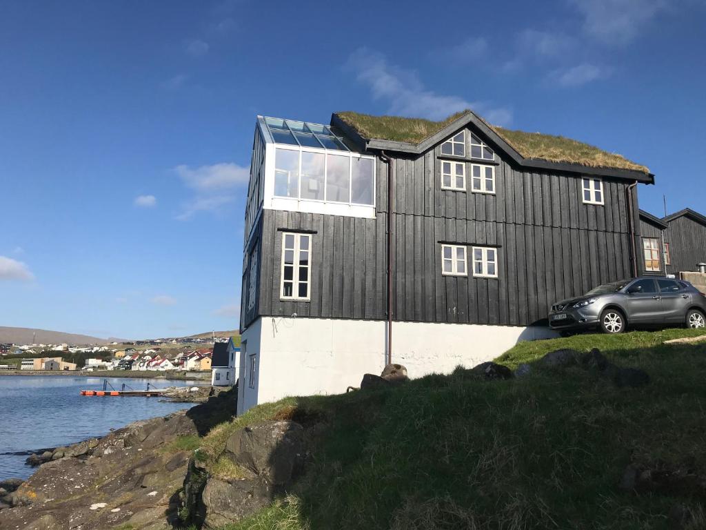MiðvágurTórhús的前面有一辆汽车停放的黑房子