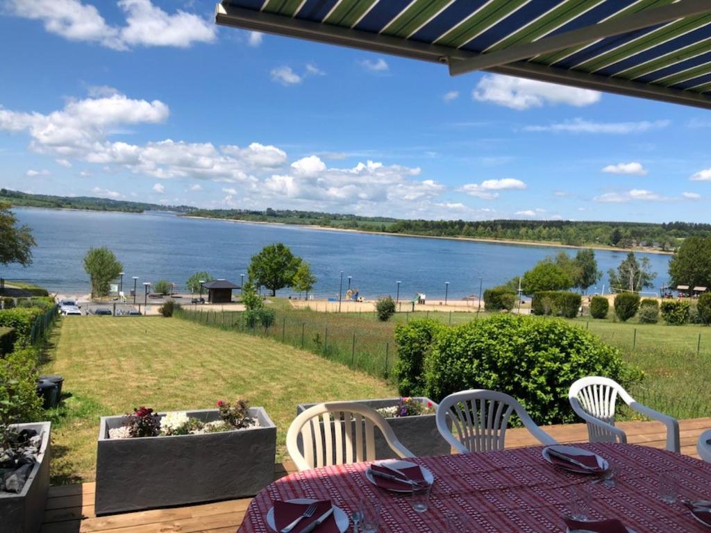 Salles-CuranMaison bord de Lac de Pareloup的湖景庭院配有桌椅