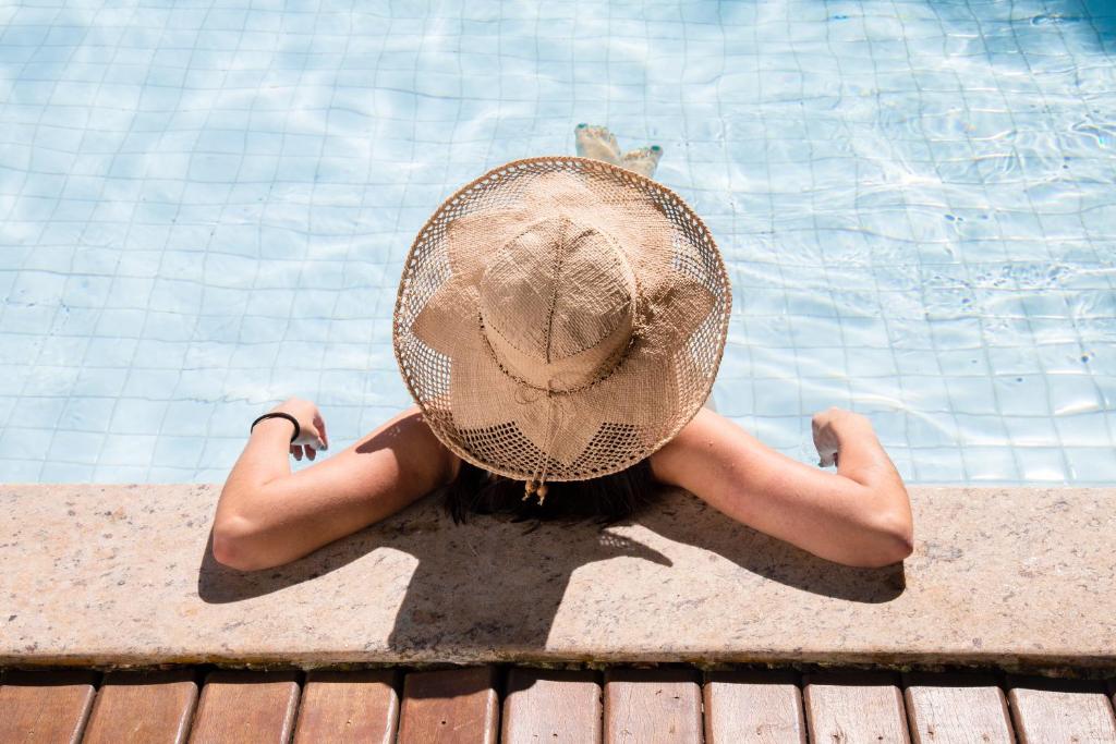 布希奥斯鲍萨达阿瓜斯克拉斯酒店的坐在游泳池旁戴帽子的女人
