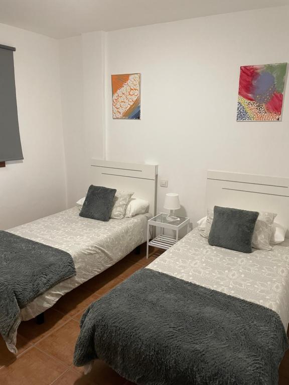 拉桑塔Apartamento los Rostros的白色墙壁客房的两张床
