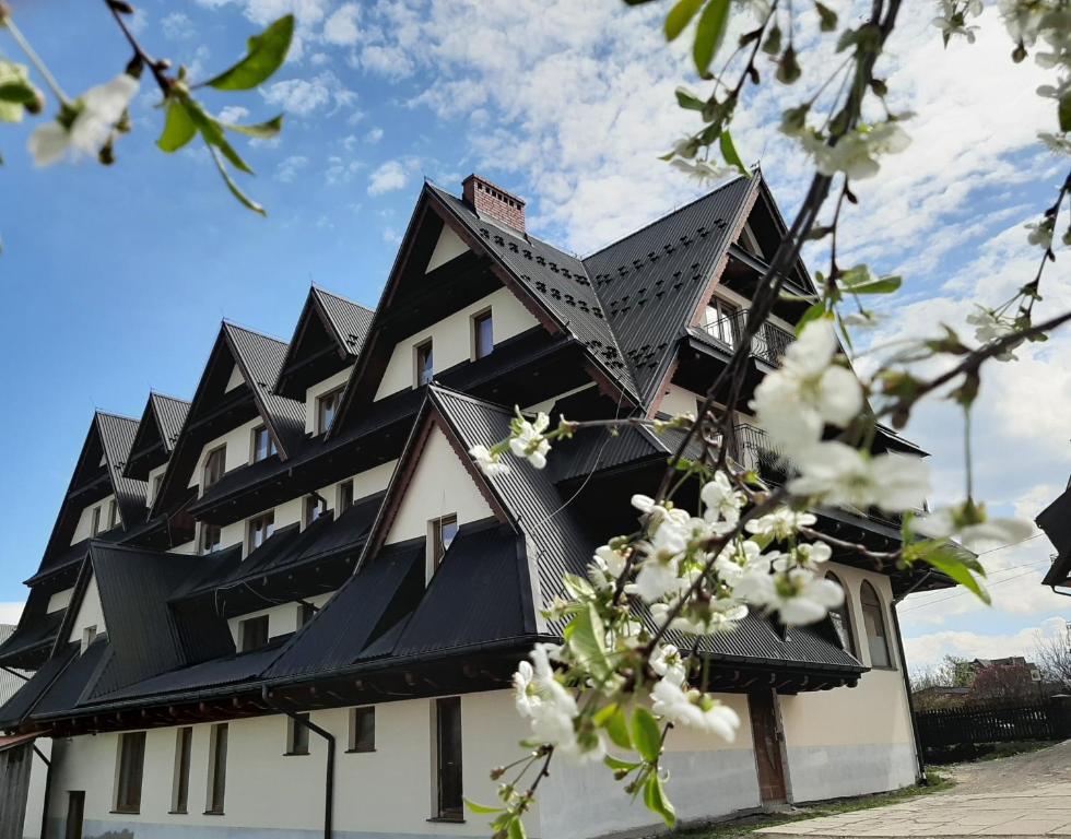 恰萨纳格拉Górski Ośrodek Wczasowy Kościelec的白色花朵的黑色屋顶建筑