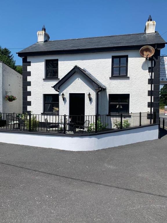 Ó MéithThe Wee House, Omeath的前面有黑色围栏的白色房子