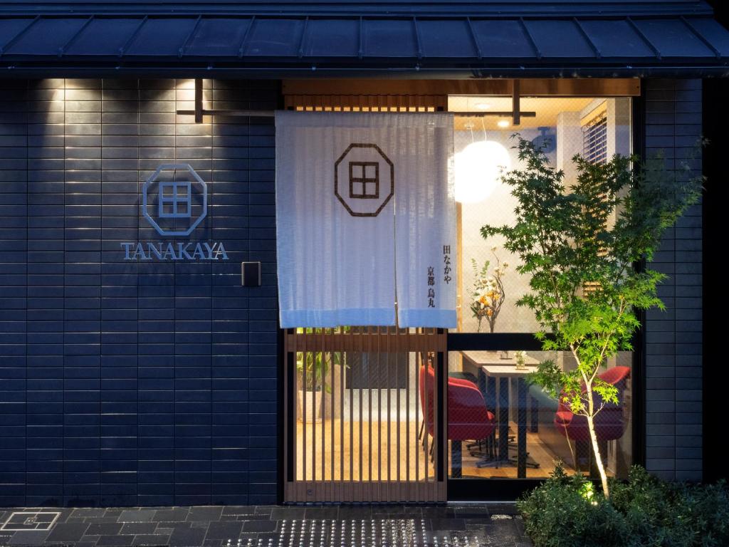 京都Tanakaya Kyoto Karasuma的大楼的前门,配有桌椅