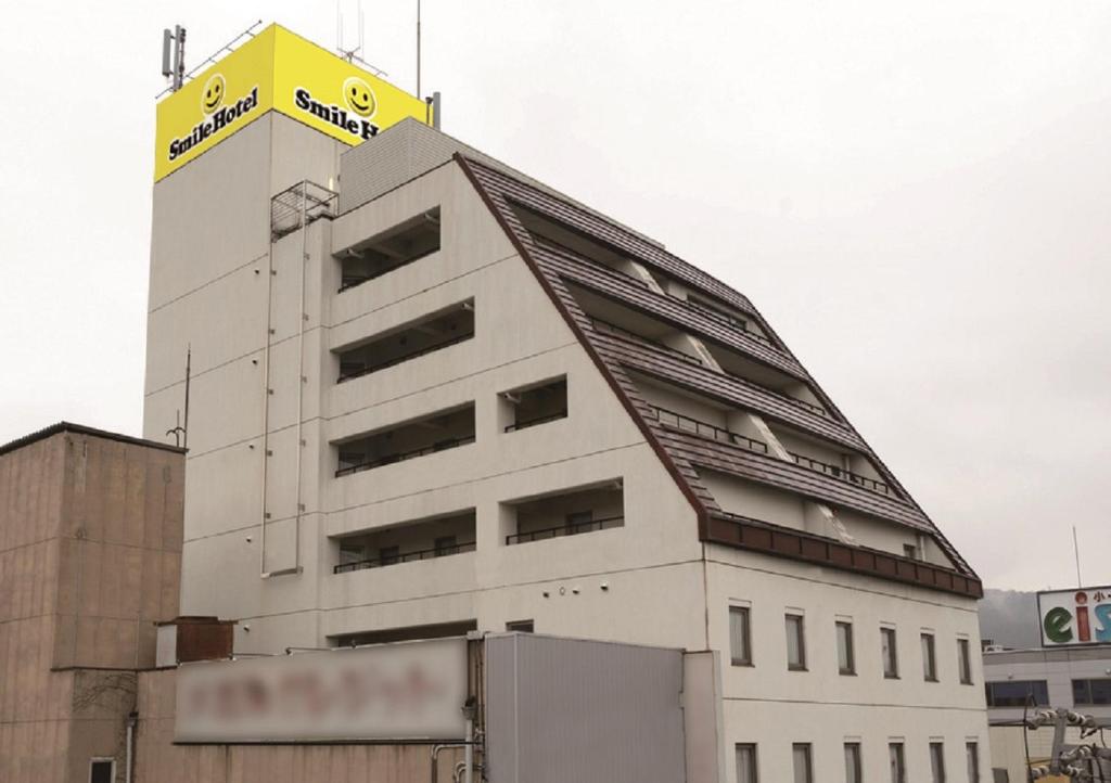名张Smile Hotel Nabari的上面有黄色标志的白色建筑