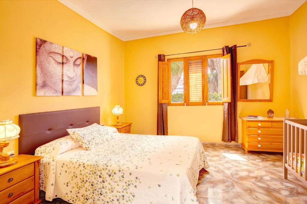 SardinaCasa Eli的一间卧室设有黄色的墙壁、一张床和一张婴儿床。