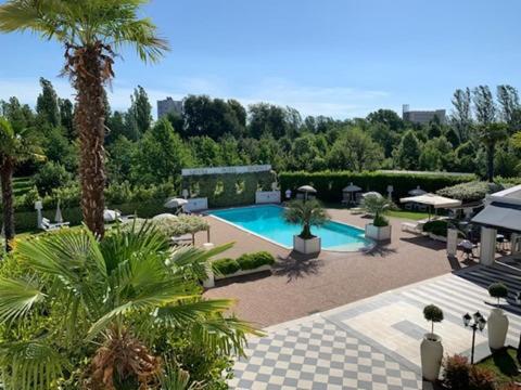 博洛尼亚萨沃亚摄政酒店的一个带游泳池和棕榈树的庭院