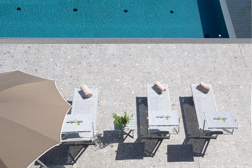 萨龙诺佩拉尔瓦汽车旅馆的一组白色躺椅,位于游泳池旁