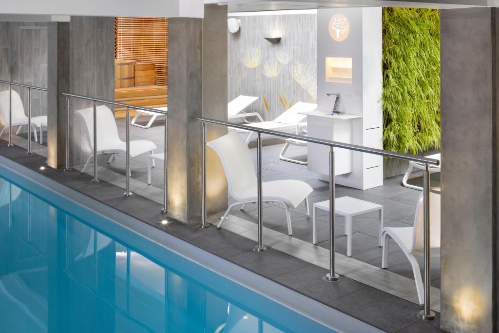 莱蓬特Terre de Provence Hôtel & Spa的大楼旁的游泳池配有桌椅