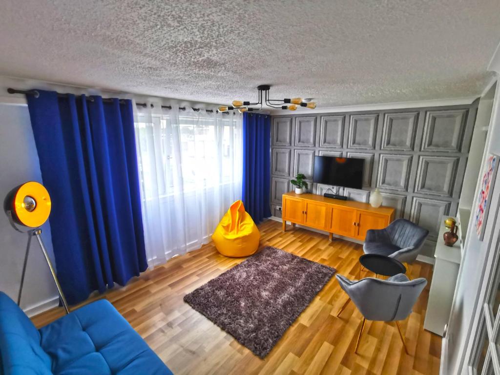 格拉斯哥Glasgow Apartment Cozy and ultramodern的客厅配有蓝色窗帘和蓝色沙发