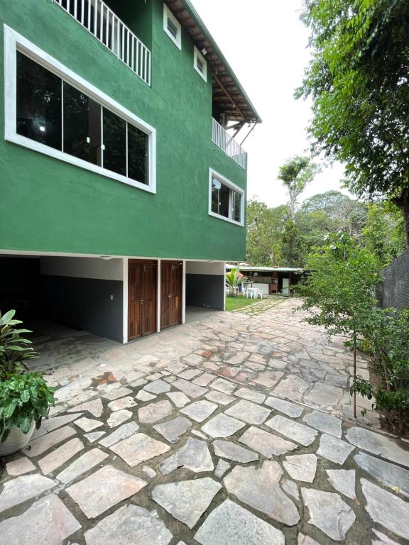 伦索伊斯Village Brasil, Lençóis的一座绿色建筑,前面有石头车道