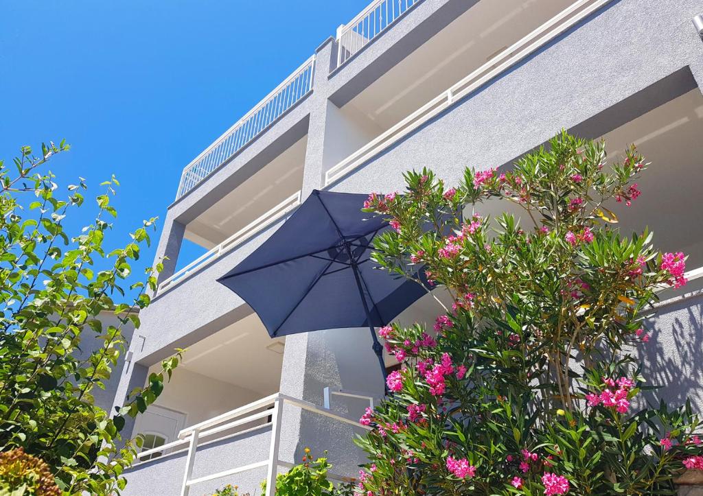 布雷拉Villa Skalinada with sea view的鲜花建筑前的蓝色伞