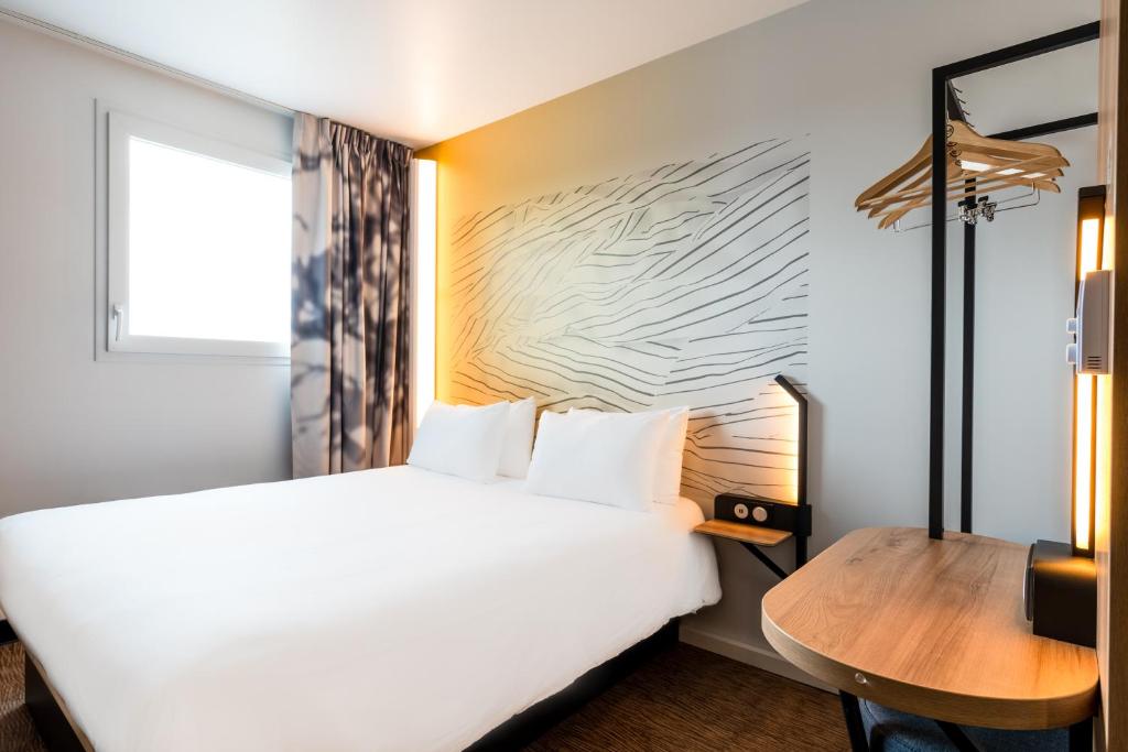 马尔利港B&B HOTEL Le Port Marly Saint Germain en Laye的酒店客房配有一张床铺和一张桌子。