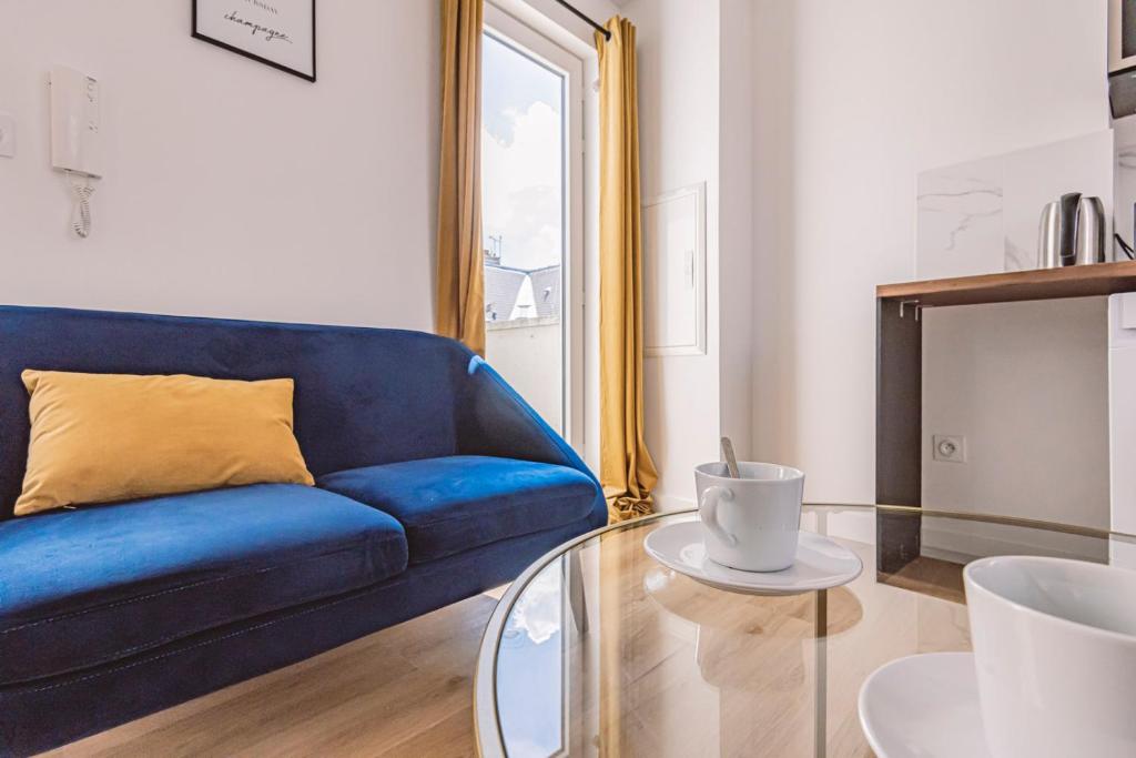 兰斯REIMS - Place du Forum - Cathédrale - Terrasse的客厅配有蓝色沙发,设有玻璃桌