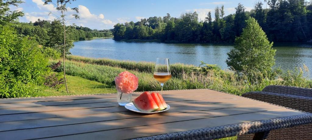 奥斯特罗达Spokojnia Ostróda的一张野餐桌,上面放着一杯葡萄酒和一块西瓜