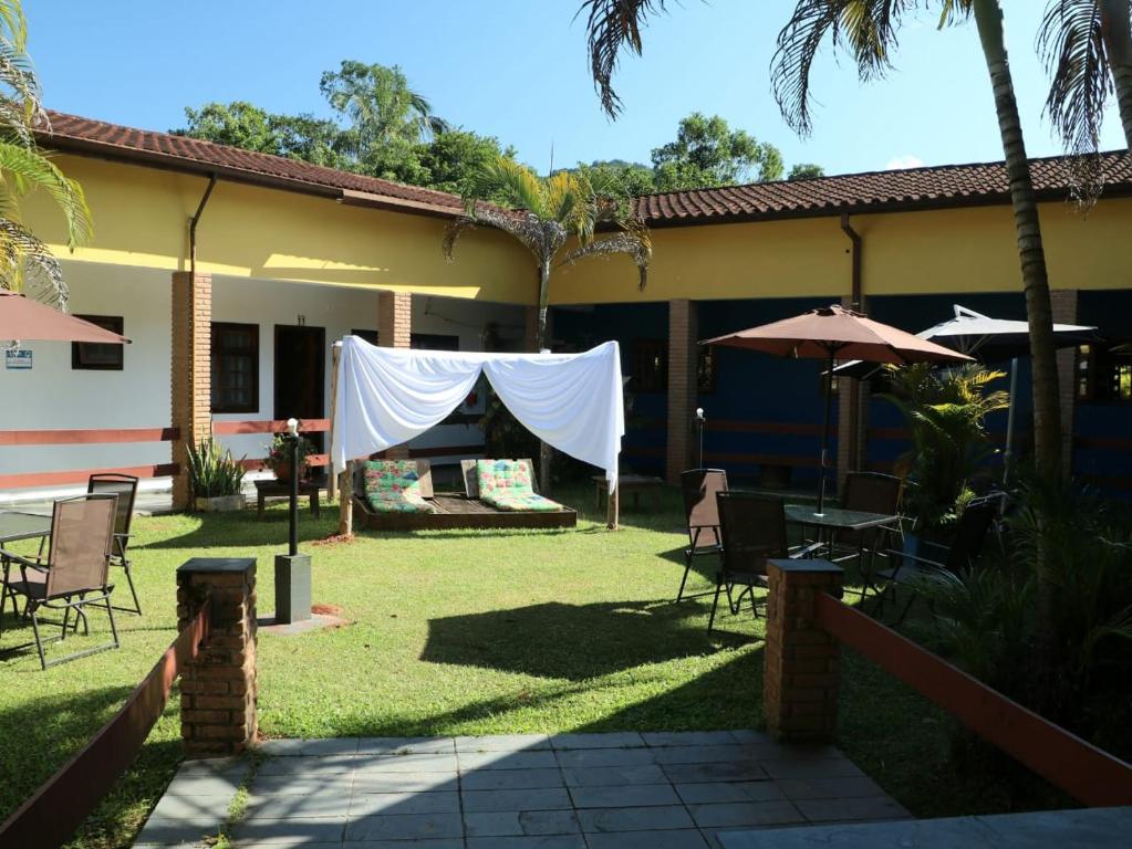 卡拉瓜塔图巴Francis Hotel Pousada的一个带桌椅和遮阳伞的庭院