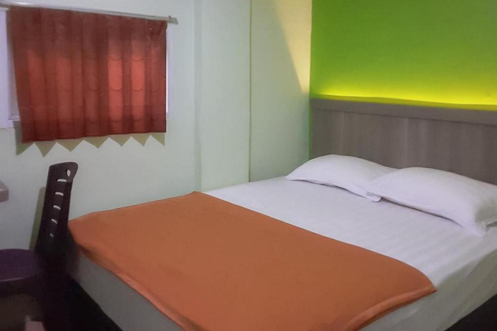 庞卡兰布翁Guest House Anak Raja Pangkalan Bun Syariah Mitra RedDoorz的一张位于带绿色和红色窗户的房间的床铺