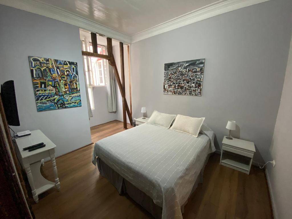瓦尔帕莱索Casa Urriola B&B的白色卧室配有一张床,墙上挂有绘画作品
