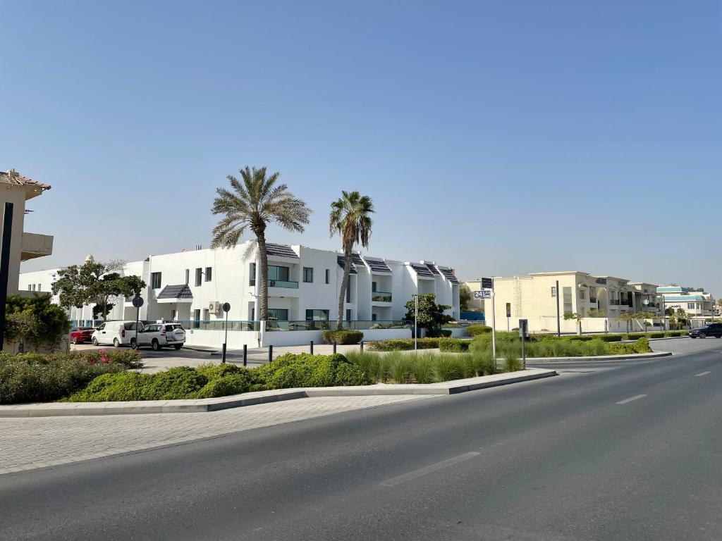 沙迦Al CORNICHE HOTEL的城市里一条空荡荡的街道,街道上有许多建筑和棕榈树