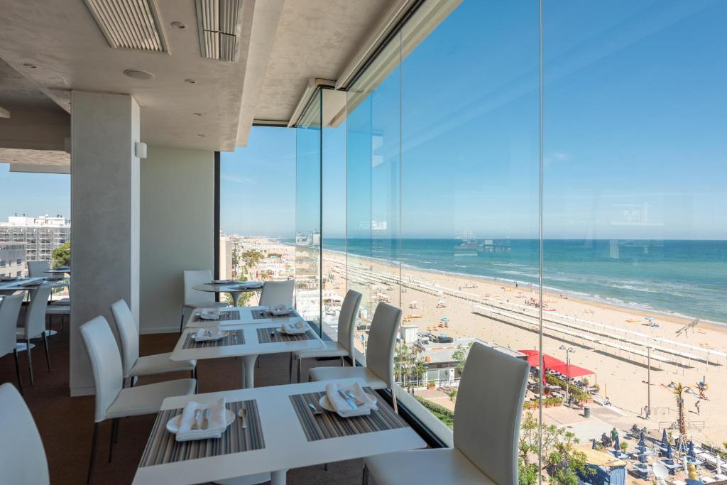里乔内康莫多雷酒店的一间带桌椅的餐厅,享有海滩美景
