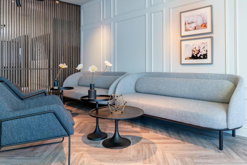 布鲁塞尔Pillows City Hotel Brussels Centre的客厅配有蓝色的沙发和2张桌子