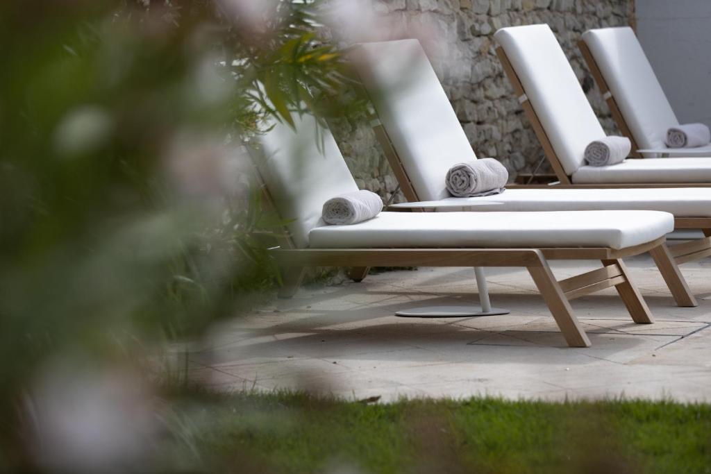 圣马丹德雷Villa Clarisse & Spa by Olivier Claire的坐在庭院里的一排白色躺椅