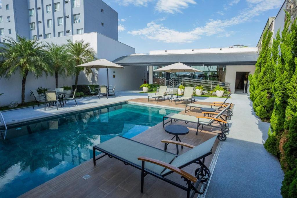 亚美利加纳佛罗伦萨酒店的一座带桌椅的游泳池位于酒店大楼旁