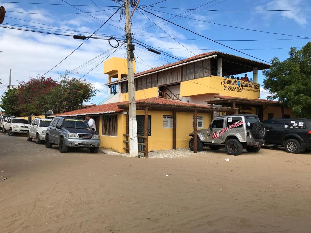 加利纽斯Pousada o Mineiro Central的一座黄色的建筑,前面有汽车停放