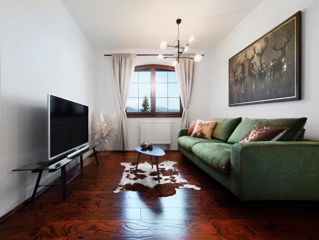 韦尔卡鲁穆尼卡TatryView Apartments by KingDubaj的客厅配有绿色沙发和电视