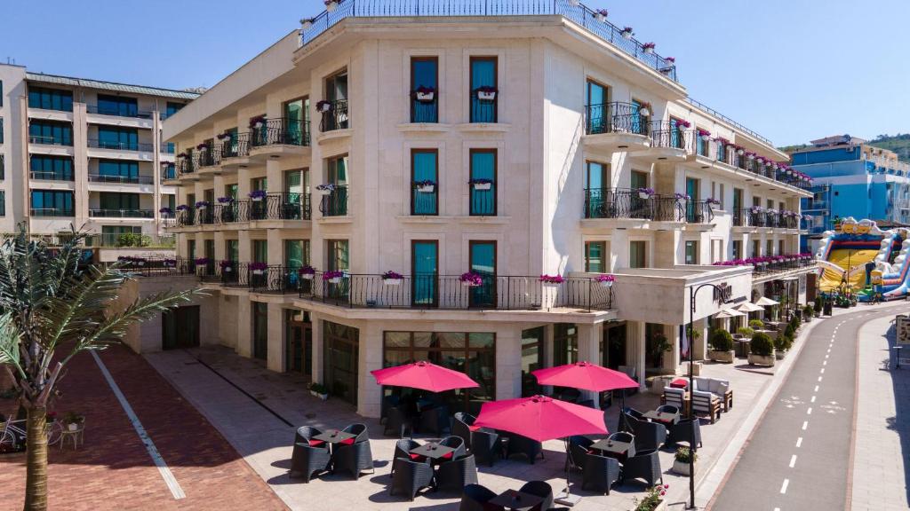巴尔奇克米斯特拉尔酒店的前面有桌子和红伞的建筑